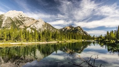 Bosque y montaña reflejados en lago Fondo de pantalla