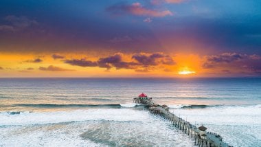Sunset in the beach in pier next to waves Wallpaper