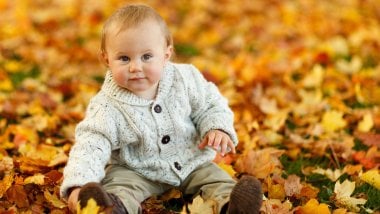 Un bebé en hojas de otoño Fondo de pantalla