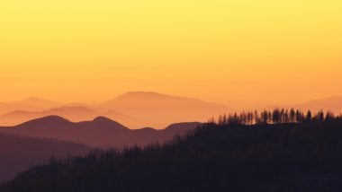 Mountains in forest at sunset Wallpaper