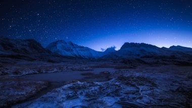 Starry night sky above the snowy mountains Wallpaper