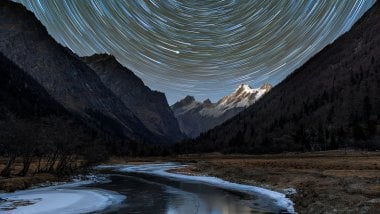 Stars in swirl in mountain landscape Wallpaper