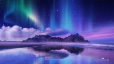 Northern lights reflected in lake in mountains Wallpaper