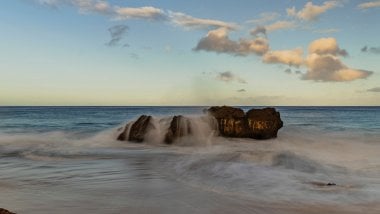 Las olas chocando con rocas en la playa Fondo de pantalla