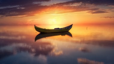 Boat in the middle of lake at sunset Wallpaper