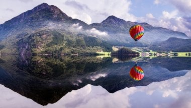Mountains reflected on lake with hot air balloon Wallpaper