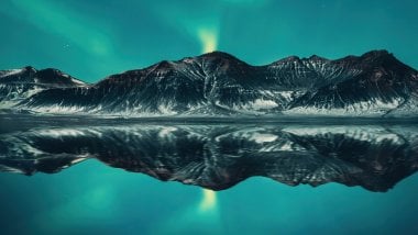 Northern lights reflected with mountains in lake Wallpaper