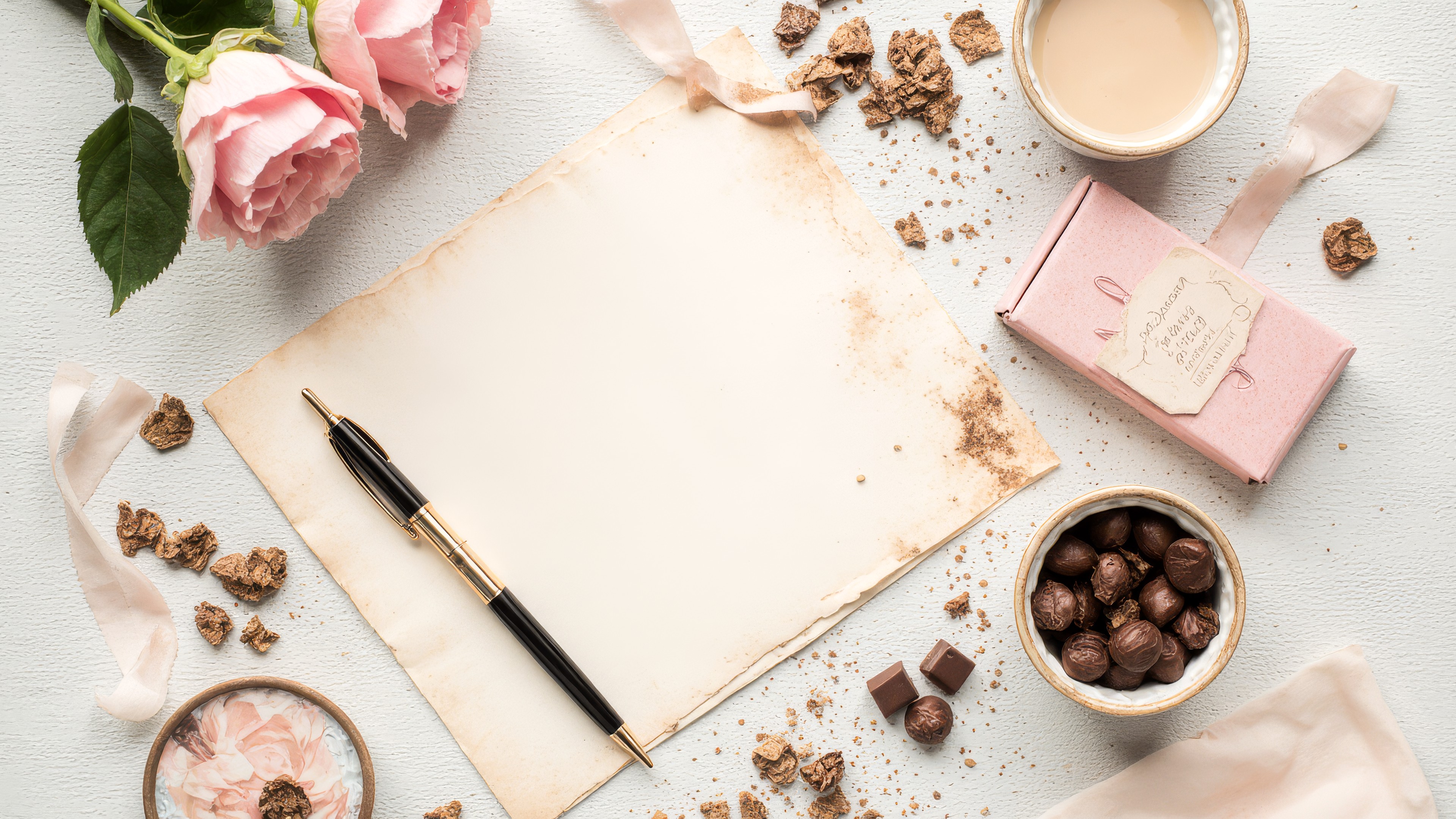 Aesthetic Photograph of a vintage paper letter with a pen, rose petals, and chocolates in soft pastel colorsWallpaper