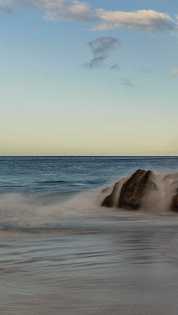 Fondos de pantalla Las olas chocando con rocas en la playa Vertical